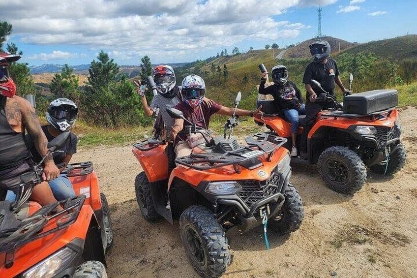 A group of people on ATVs in a dirt area with hills in the background. 2