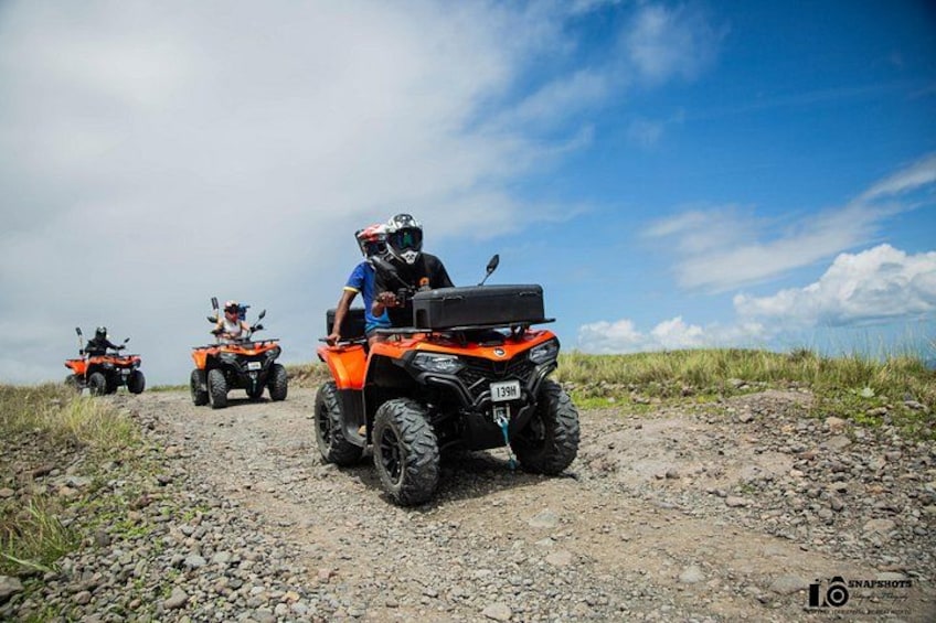 Three off-road vehicles on a gravel path with a clear sky. 1