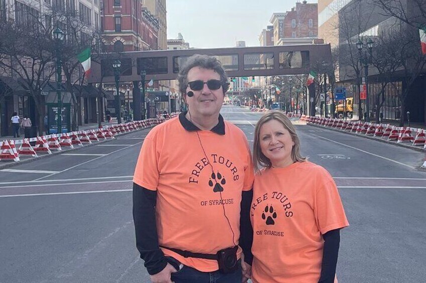 Deux personnes portant des t-shirts orange ornés d’empreintes de pattes et de l’inscription « VISITES GUIDÉES GRATUITES DE STRAUSS ». 2
