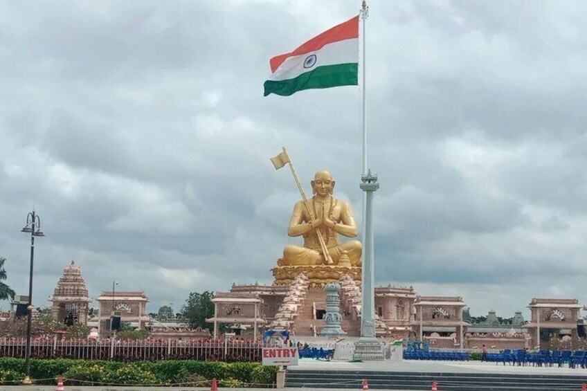 En stor gylden statue med et flag, omgivet af tempelbygninger. 4