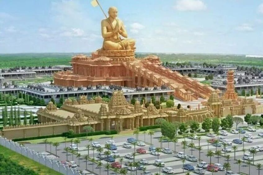 En stor gylden statue af en siddende figur øverst på et tempelkompleks med detaljeret arkitektur og en parkeringsplads i forgrunden. 3