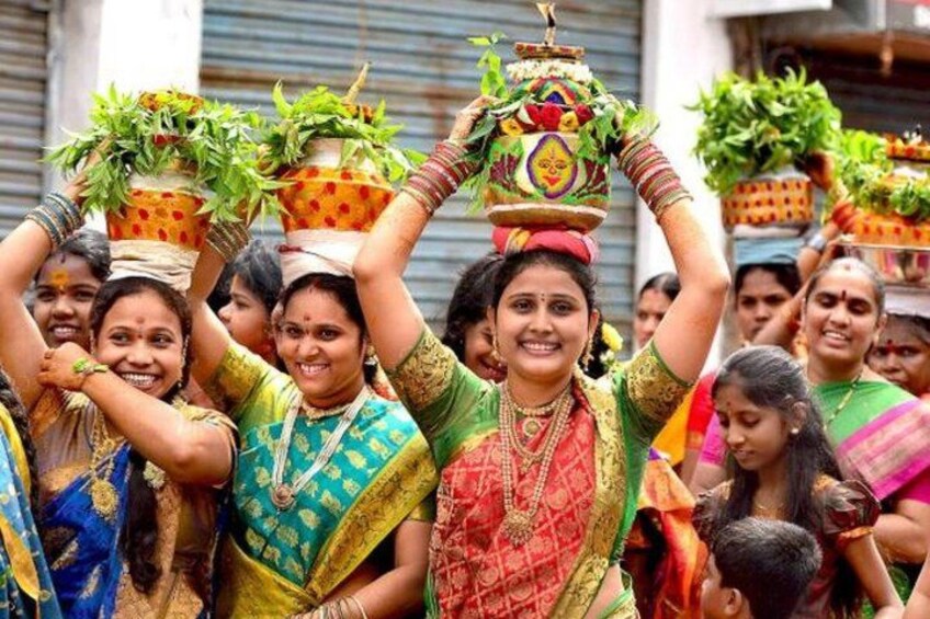 Women in colorful traditional attire carrying pots on their heads. 3