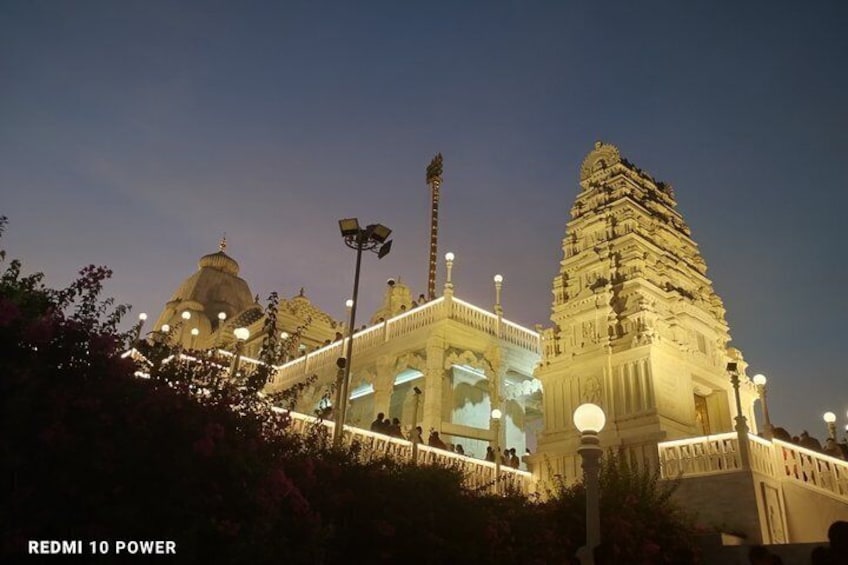 A temple with a large central tower and a smaller dome, both illuminated at night. 2