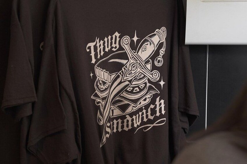 En svart t-shirt med ett grafiskt motiv och text. 2