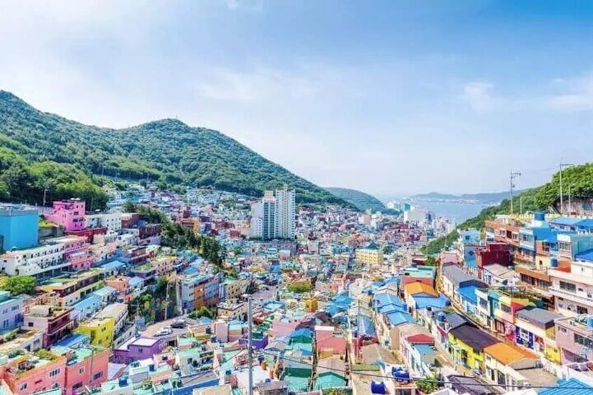 Una zona urbana densamente poblada con edificios coloridos, rodeada de colinas verdes. 2