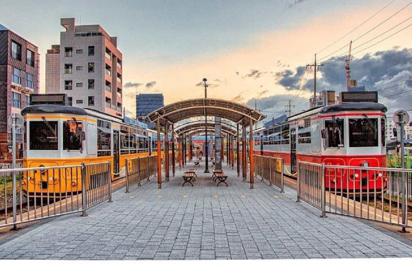 A tram station with two trams, benches, and a covered waiting area. 4