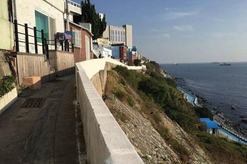 Una carretera costera con edificios, vista al mar y una estructura azul cerca del agua. 3