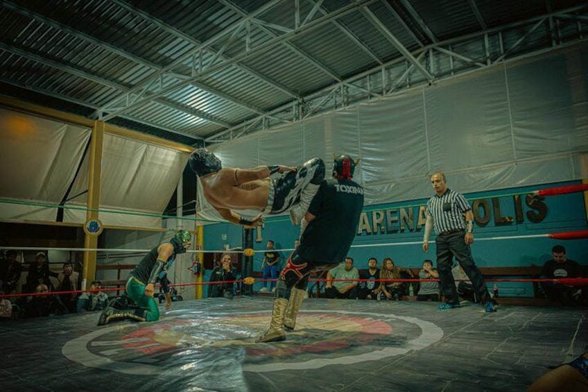 A wrestling match in a ring with a referee and spectators. 5
