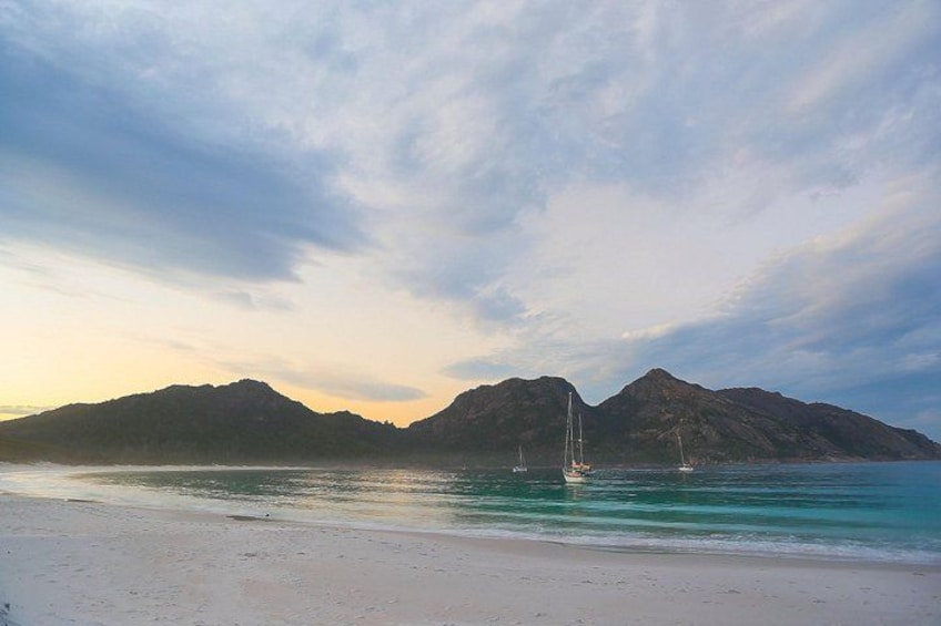 Une plage avec une eau turquoise et limpide, un rivage sablonneux et deux voiliers ancrés près du rivage. 2