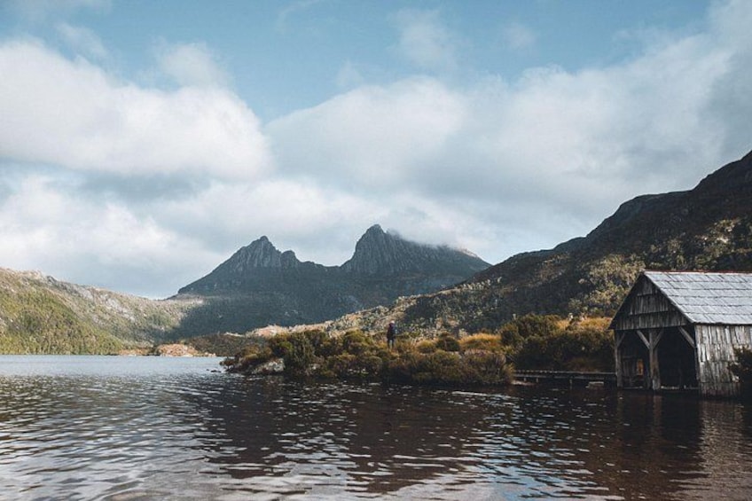 Une structure en bois au bord d’un lac, avec des montagnes en arrière-plan. 1