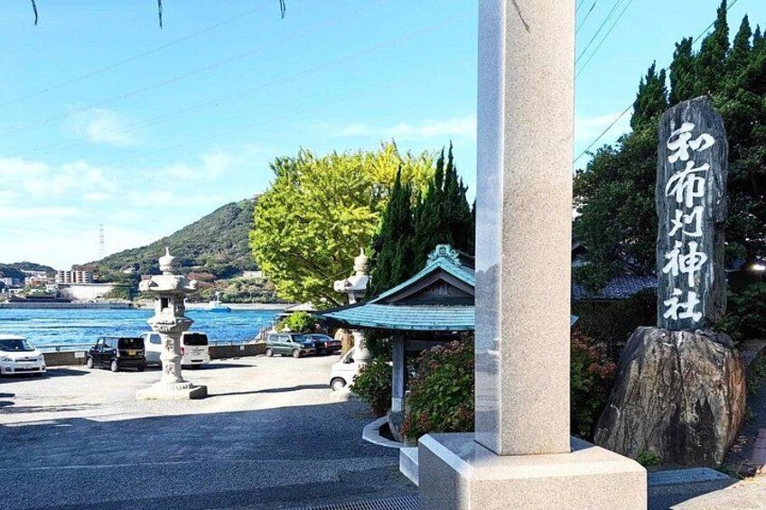 A parking area with a stone monument, a traditional building, and a view of a body of water. 5