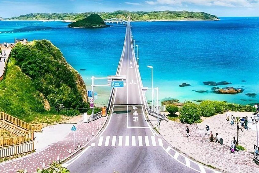 A coastal road with a bridge, a beach, and a clear blue sea. 2
