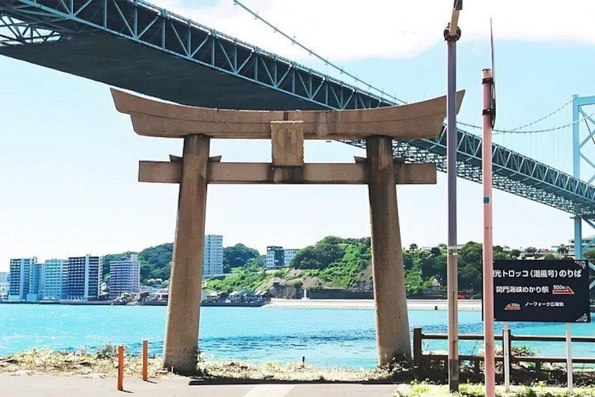 A torii gate, a suspension bridge, and a cityscape with buildings and a body of water. 4