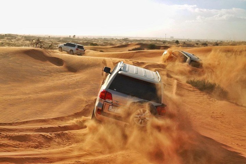 Een witte SUV rijdt door een woestijn met zandduinen. 1