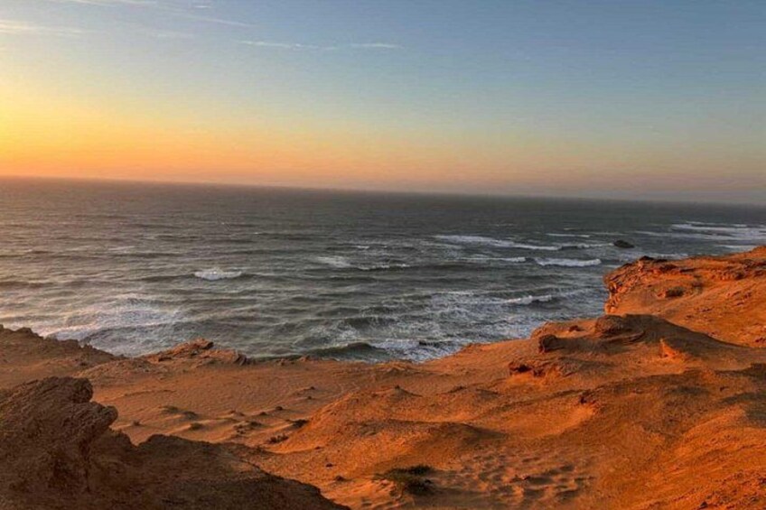 A coastal landscape with a rocky foreground and the ocean in the background. 2
