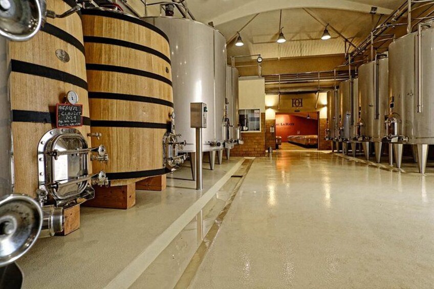 A brewery interior with wooden barrels, stainless steel tanks, and a polished floor. 3