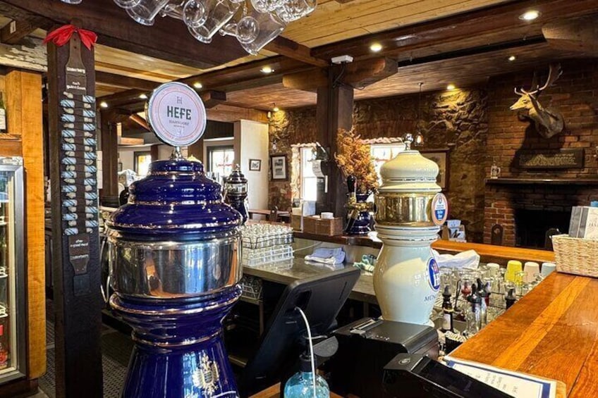 A bar with a wooden interior, a large blue beer dispenser, and a white beer dispenser. 2