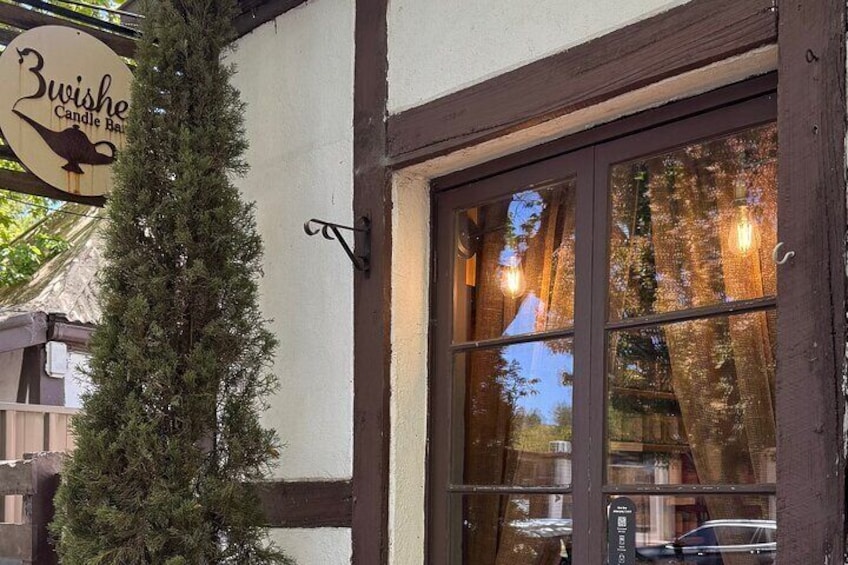 A building with a sign reading "Bwise Candle Bar" and a large window reflecting trees and lights. 3