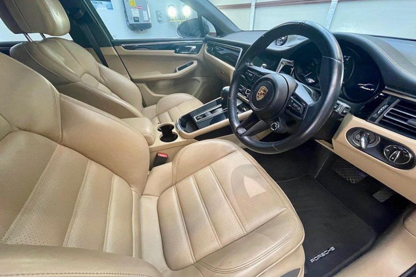 Een auto interieur met beiges leren stoelen, een stuurwiel en een middenconsole. 4