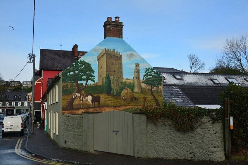 A mural on a building depicting a castle, sheep, and a tower. 5