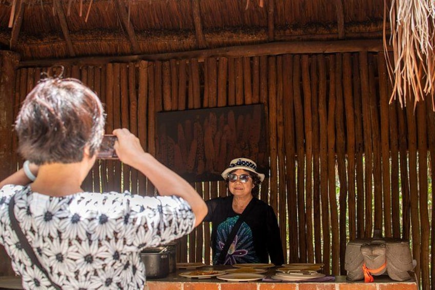Una persona fotografiando a otra en un entorno rústico con paredes de madera y techo de paja. 3