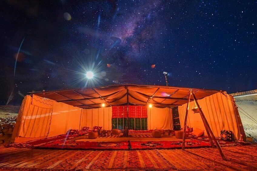 Tienda de campaña instalada sobre una alfombra estampada bajo un cielo estrellado. 5