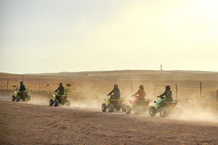 Cuatro personas conduciendo cuatrimotos por un camino polvoriento en un paisaje desértico. 3