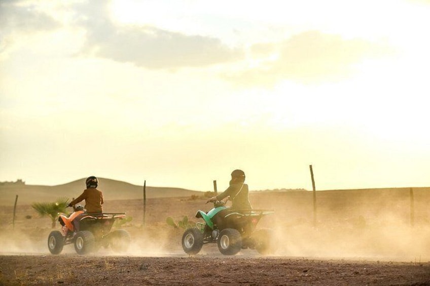 Dos personas paseando en cuatrimotos por un sendero polvoriento, con una cerca y colinas al fondo. 4