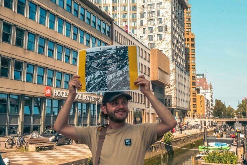 Una persona sosteniendo un letrero amarillo y negro con un mapa, de pie frente a un edificio con un cartel que dice 'HOGES'. 5