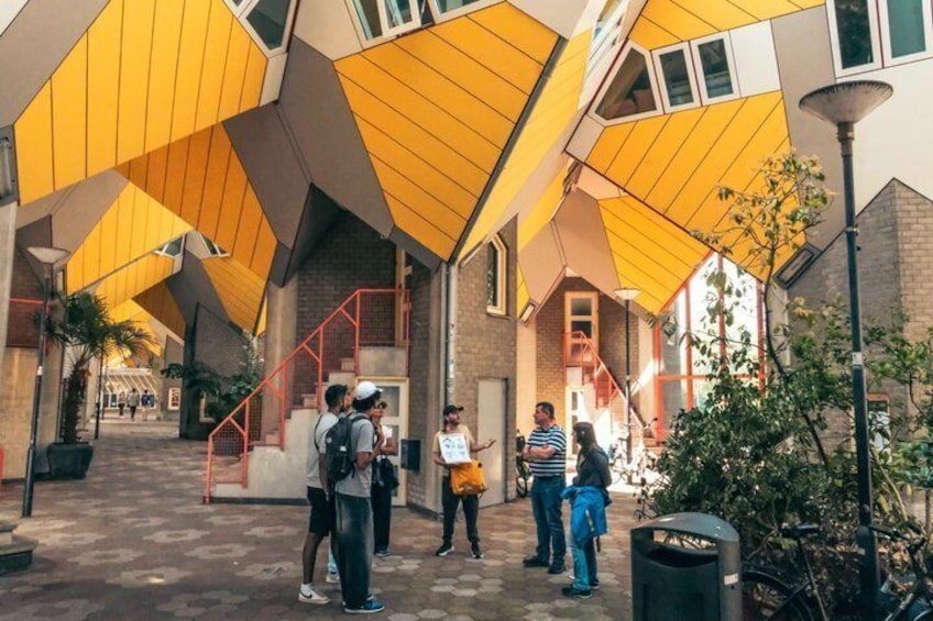 Un edificio con techos triangulares amarillos y paredes de ladrillo, una escalera y personas en primer plano. 1
