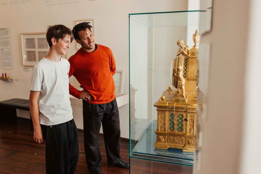 Dos personas en un museo, con una estatua dorada en una vitrina. 4