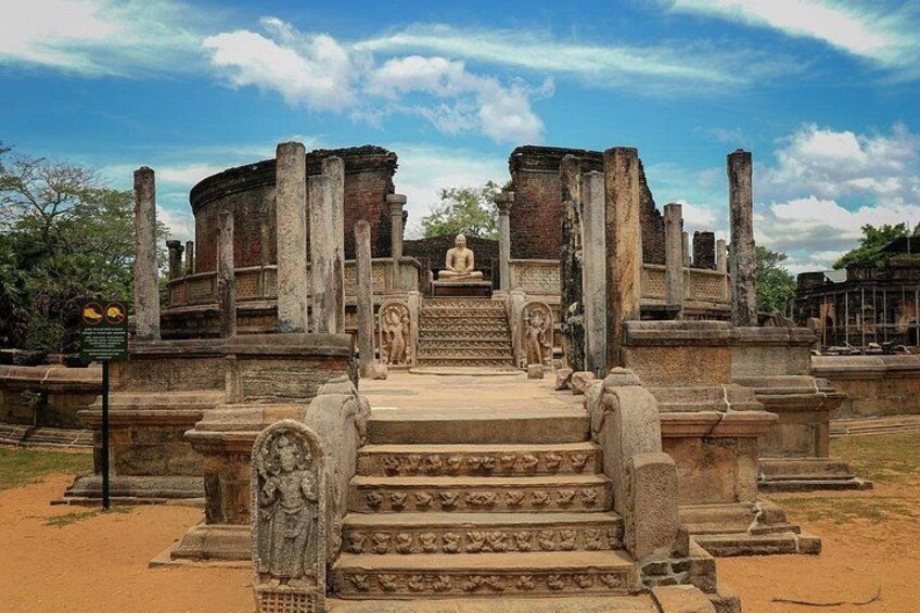Ancient stone ruins with a central statue, steps leading up to it, and a clear sky. 1