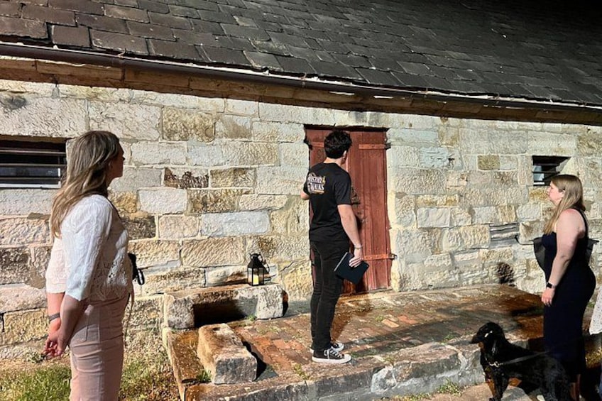 A stone building with a wooden door, a stone bench, and a dog. 2