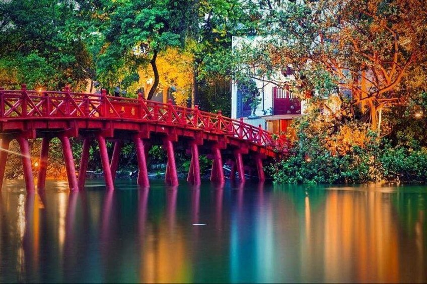 Eine rote Brücke über ruhigem Wasser, umgeben von üppigem Grün und Bäumen. 2