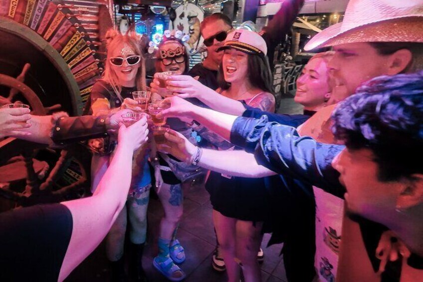 A group of people toasting with drinks in a dimly lit setting. 2