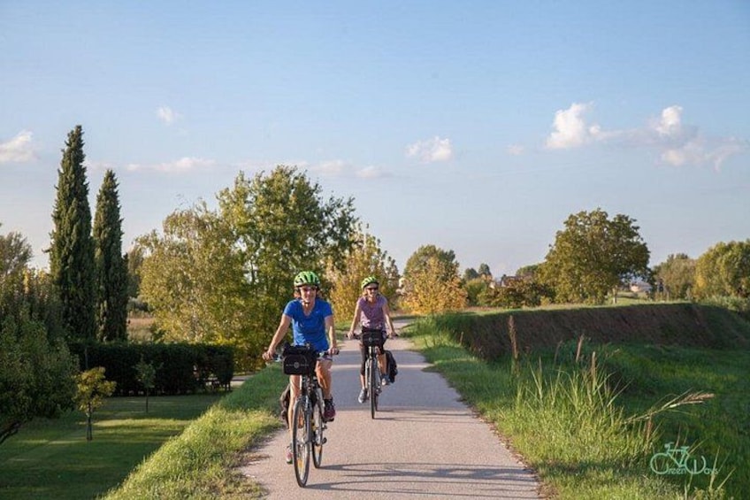 Dos ciclistas en un sendero pavimentado rodeado de follaje y árboles. 4