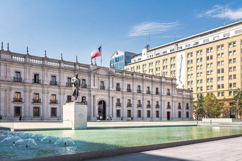 Un grand bâtiment avec une statue devant, un drapeau et une fontaine. 5