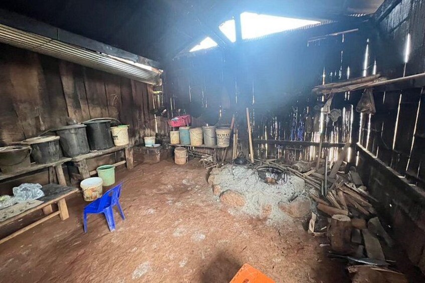 A rustic interior with wooden walls, metal barrels, and a central fire pit. 4