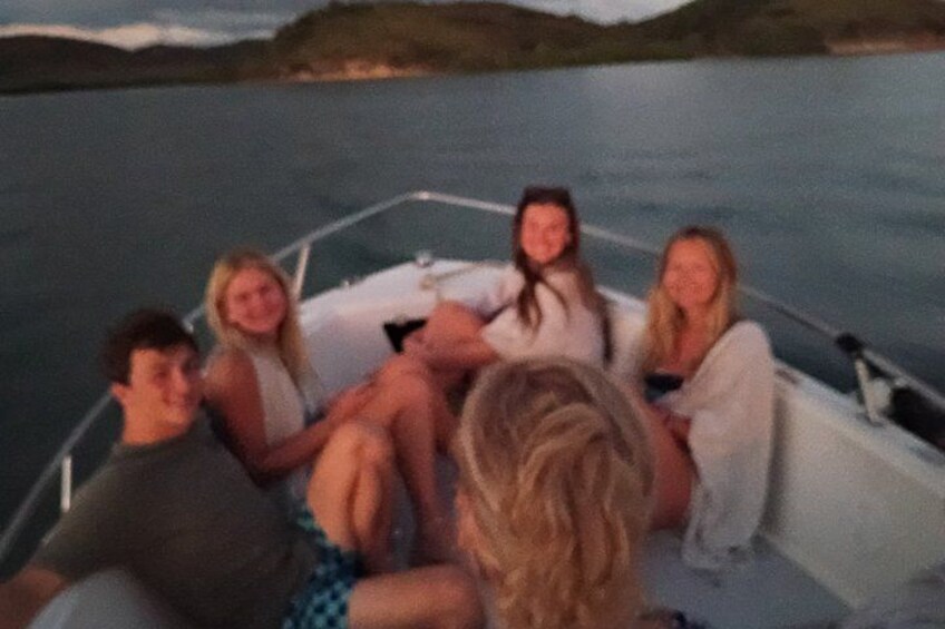 A group of people on a boat in a body of water with a hilly landscape in the background. 2
