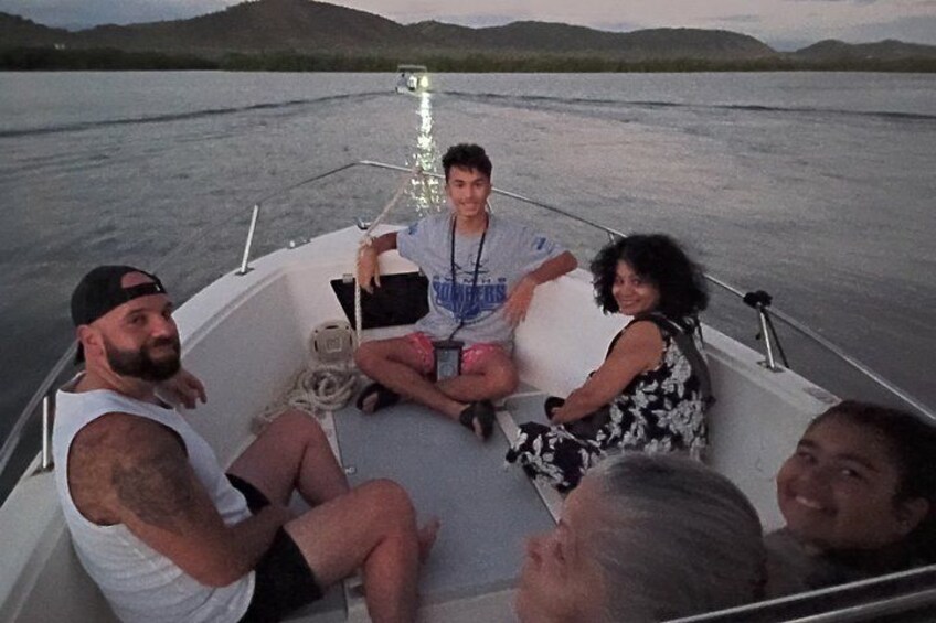A group of people on a boat with a calm body of water and hills in the background. 2