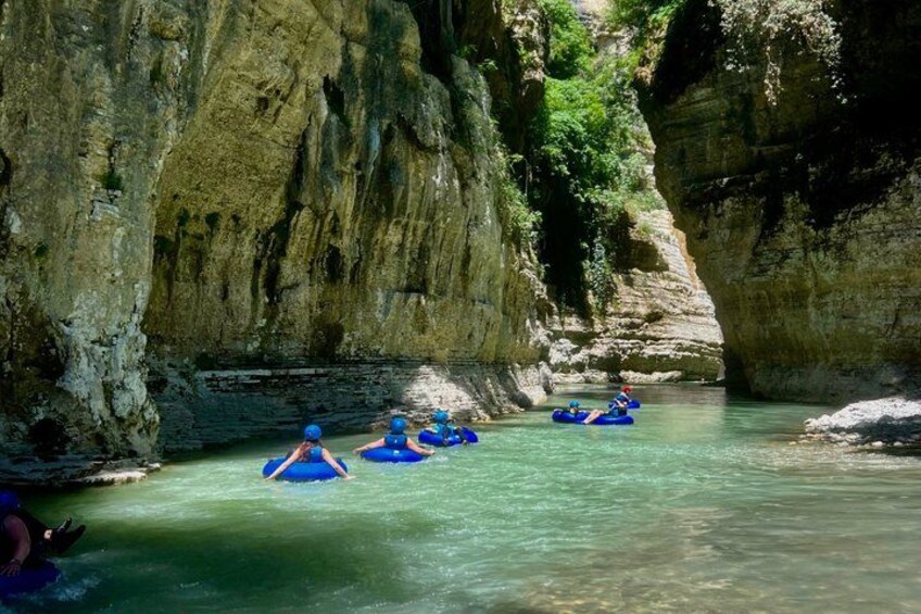 People rafting in a narrow canyon with rocky walls. 4