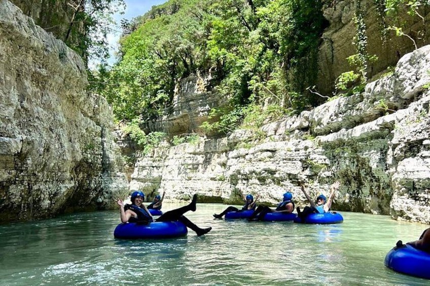 People rafting on a river surrounded by rocky cliffs and greenery. 2