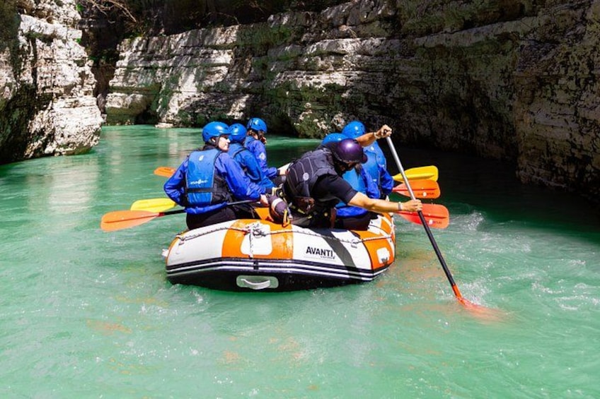 A group of people in a raft navigating a river surrounded by rocky cliffs. 5