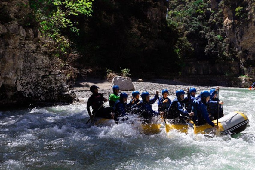 A group of people rafting on a river surrounded by rocky cliffs. 5