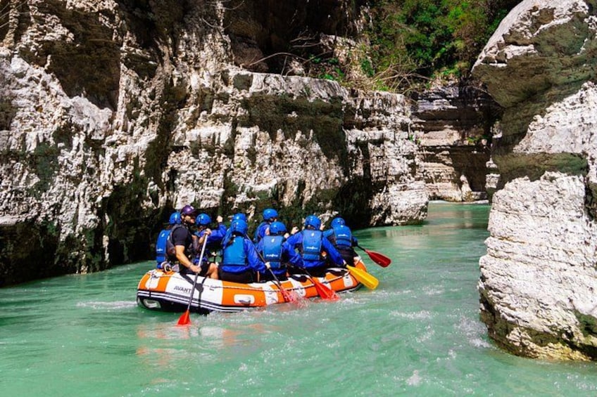 A group of people in a raft navigating a river with rocky cliffs. 5