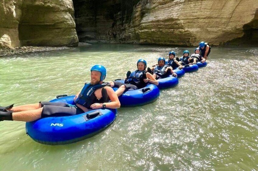 People rafting in blue inflatable tubes on a river. 5
