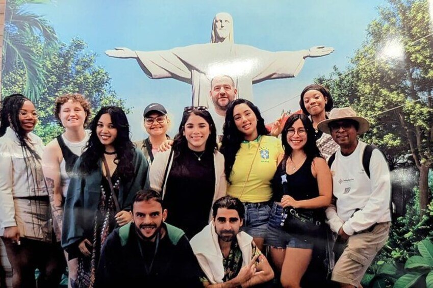 Un grupo de personas posando frente a una gran estatua con brazos extendidos. 1