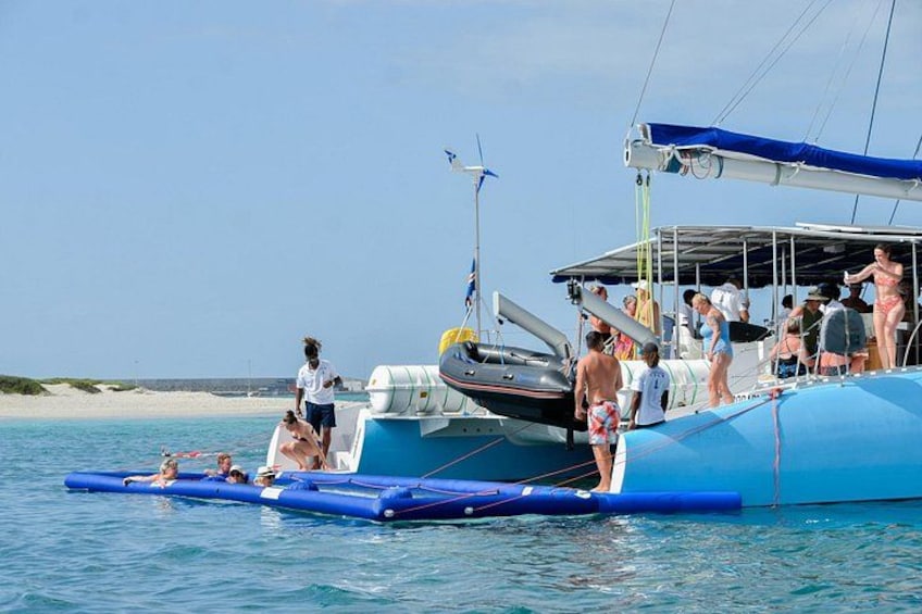 Een blauwe boot met mensen, een zandstrand en een heldere lucht. 1