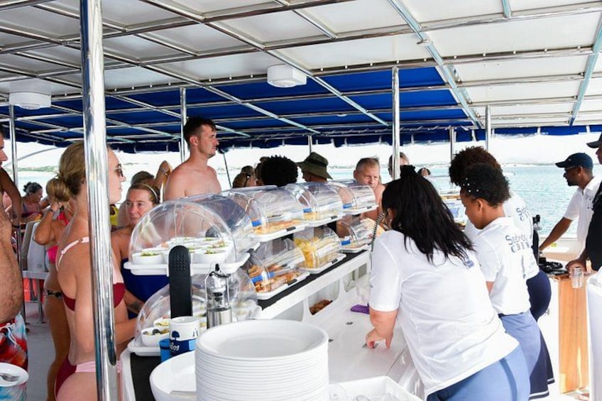 A buffet setup on a boat with people serving and serving food. 2