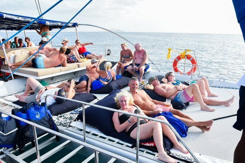 People relaxing on a boat deck with a lifebuoy and a person standing. 3
